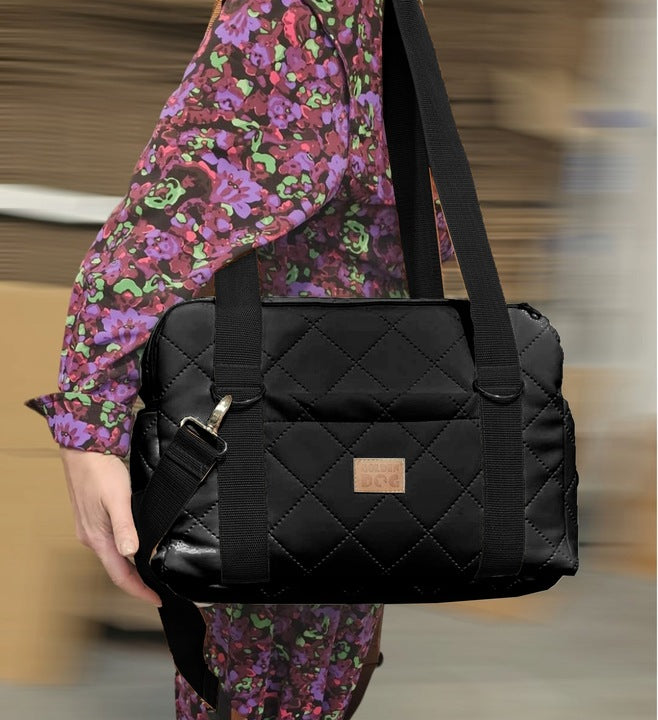 A black quilted pet carrier bag with metallic fittings and an adjustable shoulder strap, suitable for small dogs or cats—ideal for car journeys or daily walks.