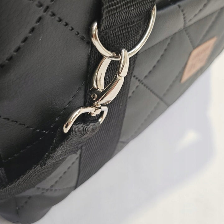 A black quilted pet carrier bag with metallic fittings and an adjustable shoulder strap, suitable for small dogs or cats—ideal for car journeys or daily walks.