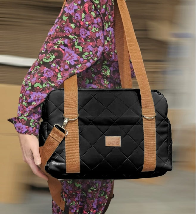 Black quilted dog travel bag with brown shoulder straps and soft plush interior; labelled “Deluxe Dog” — a stylish and secure pet carrier for small breeds.