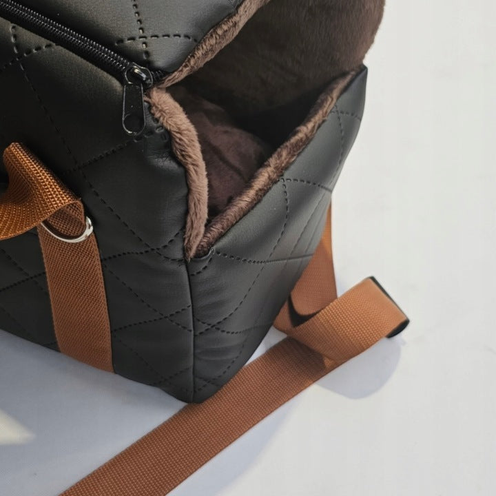 Black quilted dog travel bag with brown shoulder straps and soft plush interior; labelled “Deluxe Dog” — a stylish and secure pet carrier for small breeds.