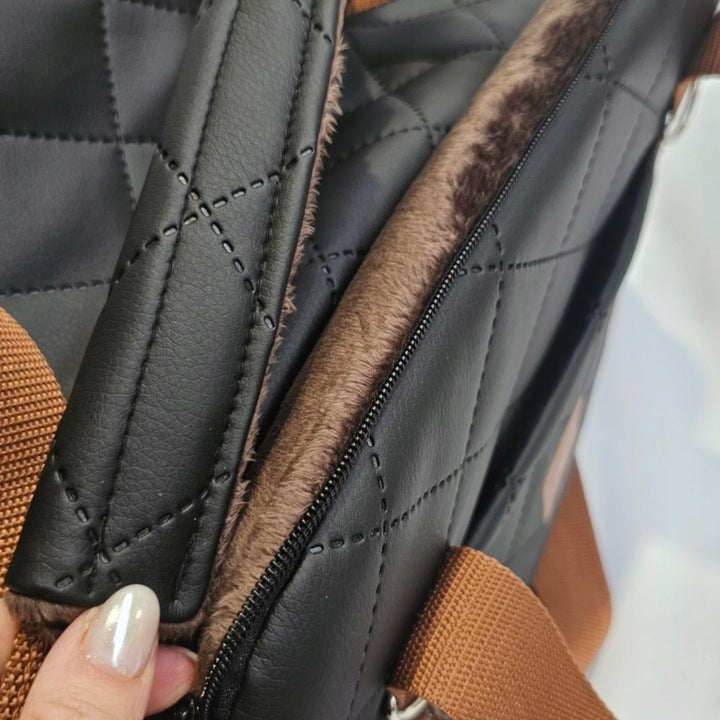 Black quilted dog travel bag with brown shoulder straps and soft plush interior; labelled “Deluxe Dog” — a stylish and secure pet carrier for small breeds.