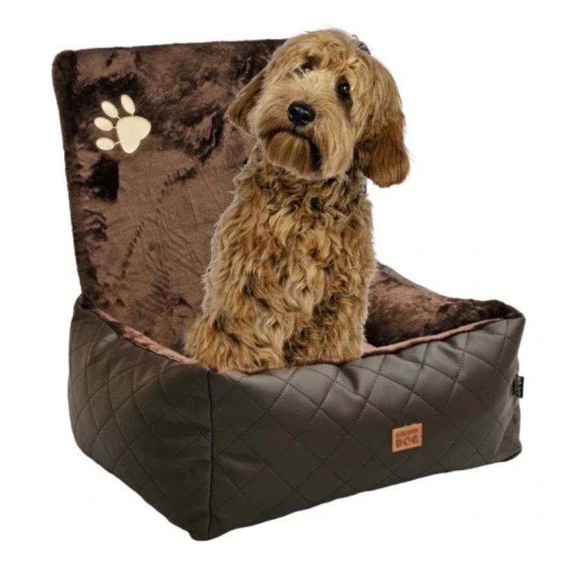Small curly-haired dog sitting in a chocolate quilted dog car seat mounted to the front passenger chair with tan leather upholstery; plush interior and zippered sides with embroidered paw detail