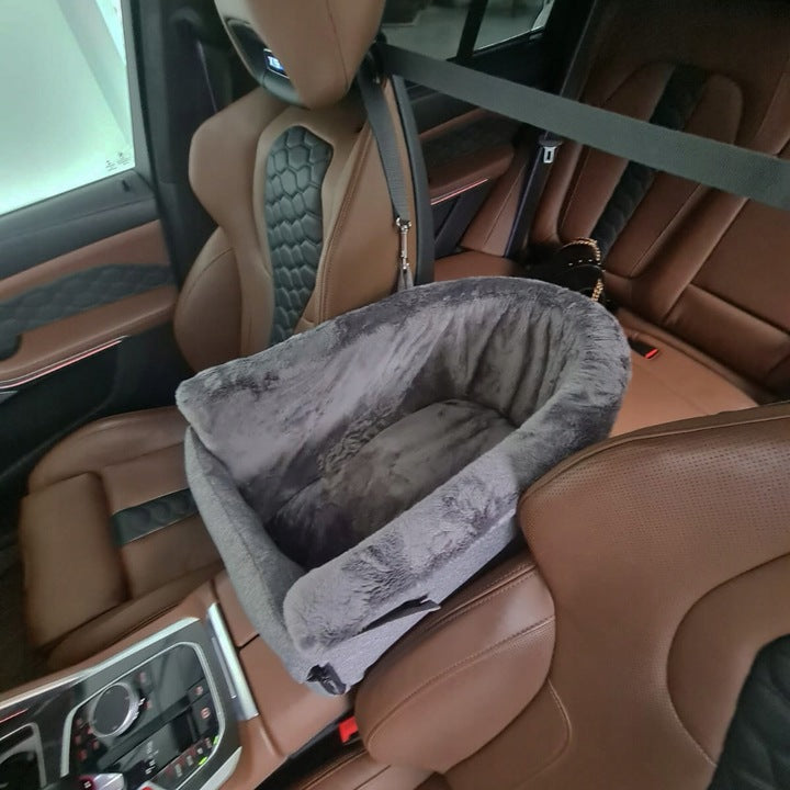 Grey dog car seat securely mounted between the front seats of a car with tan leather upholstery; features padded sides, side zip and a branded Golden Dog patch — designed for small pets to travel safely and stylishly