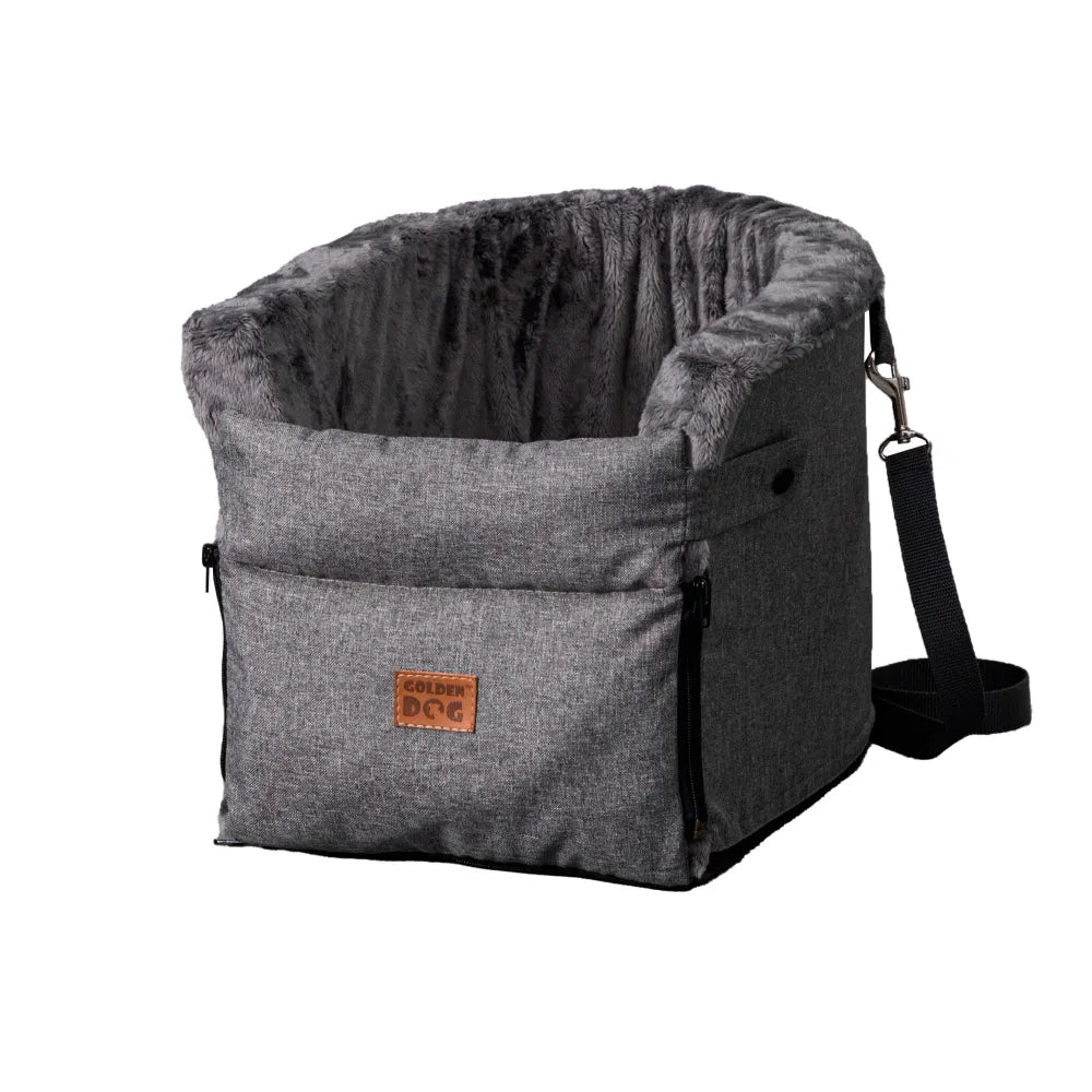 Grey dog car seat securely mounted between the front seats of a car with tan leather upholstery; features padded sides, side zip and a branded Golden Dog patch — designed for small pets to travel safely and stylishly