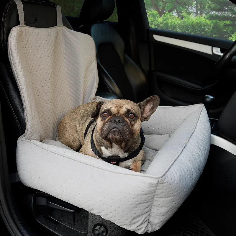 A soft, grey upholstered dog car seat with raised backrest and safety straps, designed for secure and comfortable travel in vehicles.