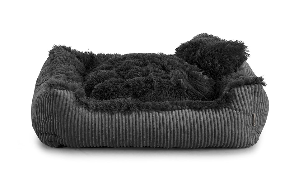 Shaggy dog bed in black colour fabric with small pillow.