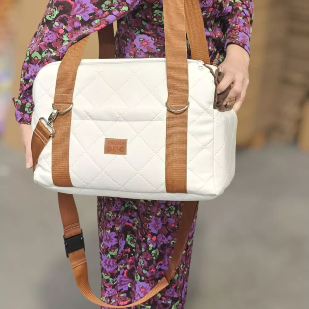 White quilted dog travel bag with brown shoulder straps and soft plush interior; — a stylish and secure pet carrier for small breeds.