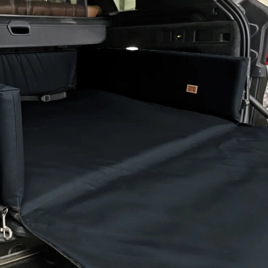 Black eco-leather boot mat for dogs fitted in a car’s cargo area — features raised foam-filled sides and bumper flap for protection, designed to shield against dirt, moisture, and scratches