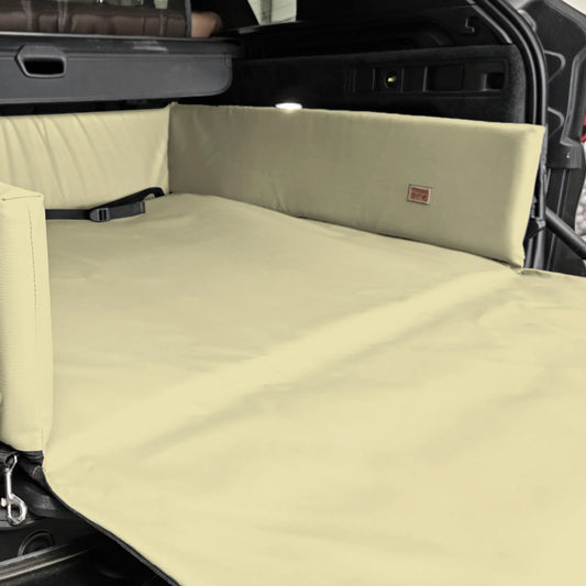 Cream eco-leather boot mat for dogs fitted in a car’s cargo area — features raised foam-filled sides and bumper flap for protection, designed to shield against dirt, moisture, and scratches