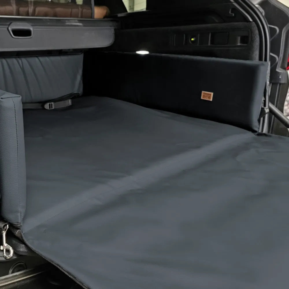 Grey eco-leather boot mat for dogs fitted in a car’s cargo area — features raised foam-filled sides and bumper flap for protection, designed to shield against dirt, moisture, and scratches