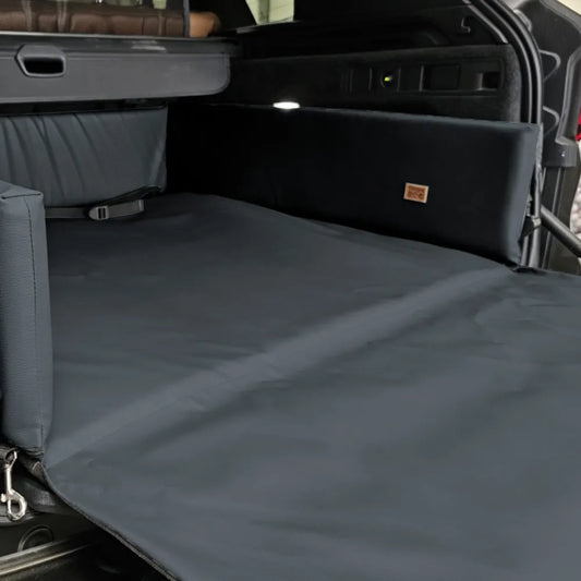 Grey eco-leather boot mat for dogs fitted in a car’s cargo area — features raised foam-filled sides and bumper flap for protection, designed to shield against dirt, moisture, and scratches