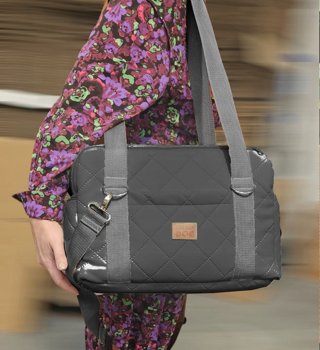 Graphite quilted dog travel bag with brown shoulder straps and soft plush interior — a stylish and secure pet carrier for small breeds.